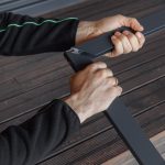 Hände, die zwei Metallrahmenstücke für Fliegengitter Tür - faltbar auf einem Holzboden zusammensetzen.